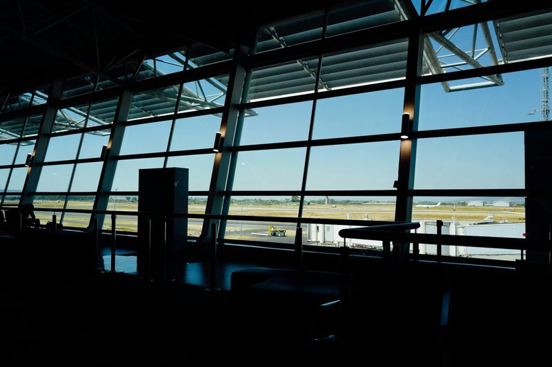 Utsikt fra en flyplassterminal mot rullebanen og et fly i solskinn