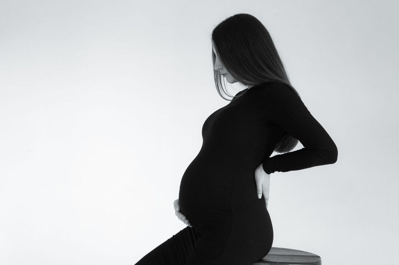 Gravid kvinne sitter og holder hånden mot korsryggen