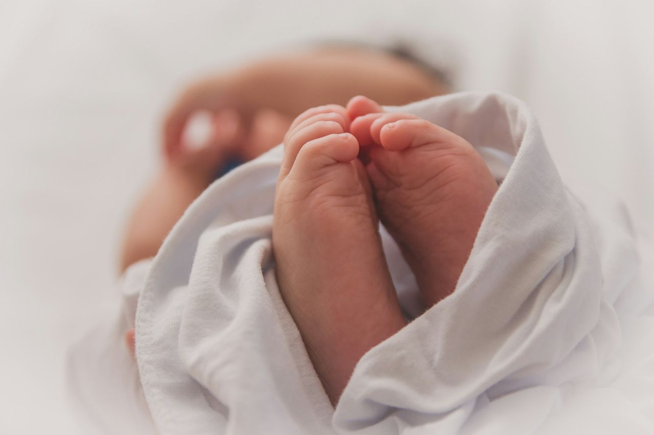 Bare babyføtter som stikker ut av et hvitt teppe